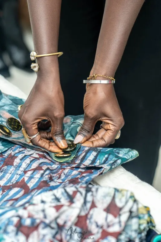 Hands arranging printed fabrics with gold jewelry