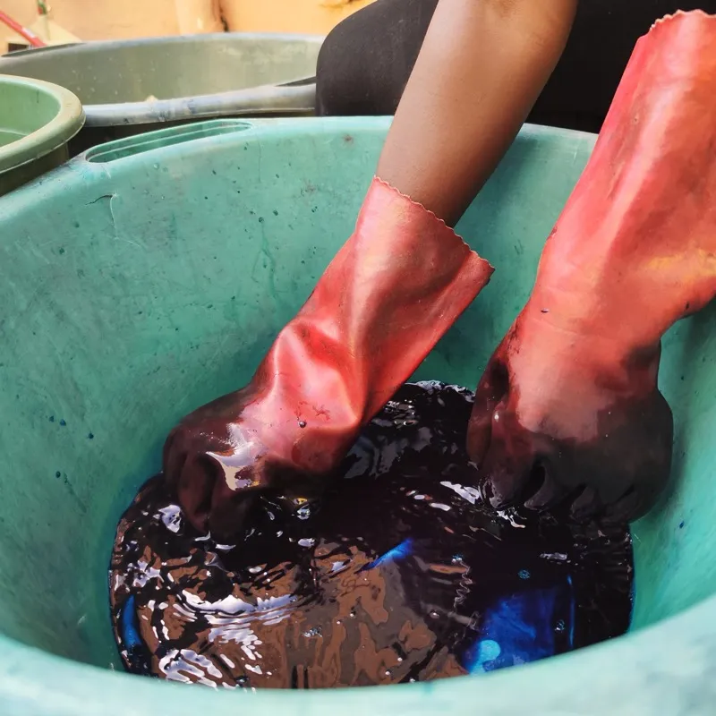 Hands plunged in indigo dye basin close-up
