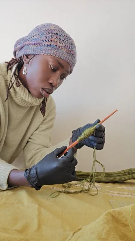 Diama crocheting with green yarn and black gloves